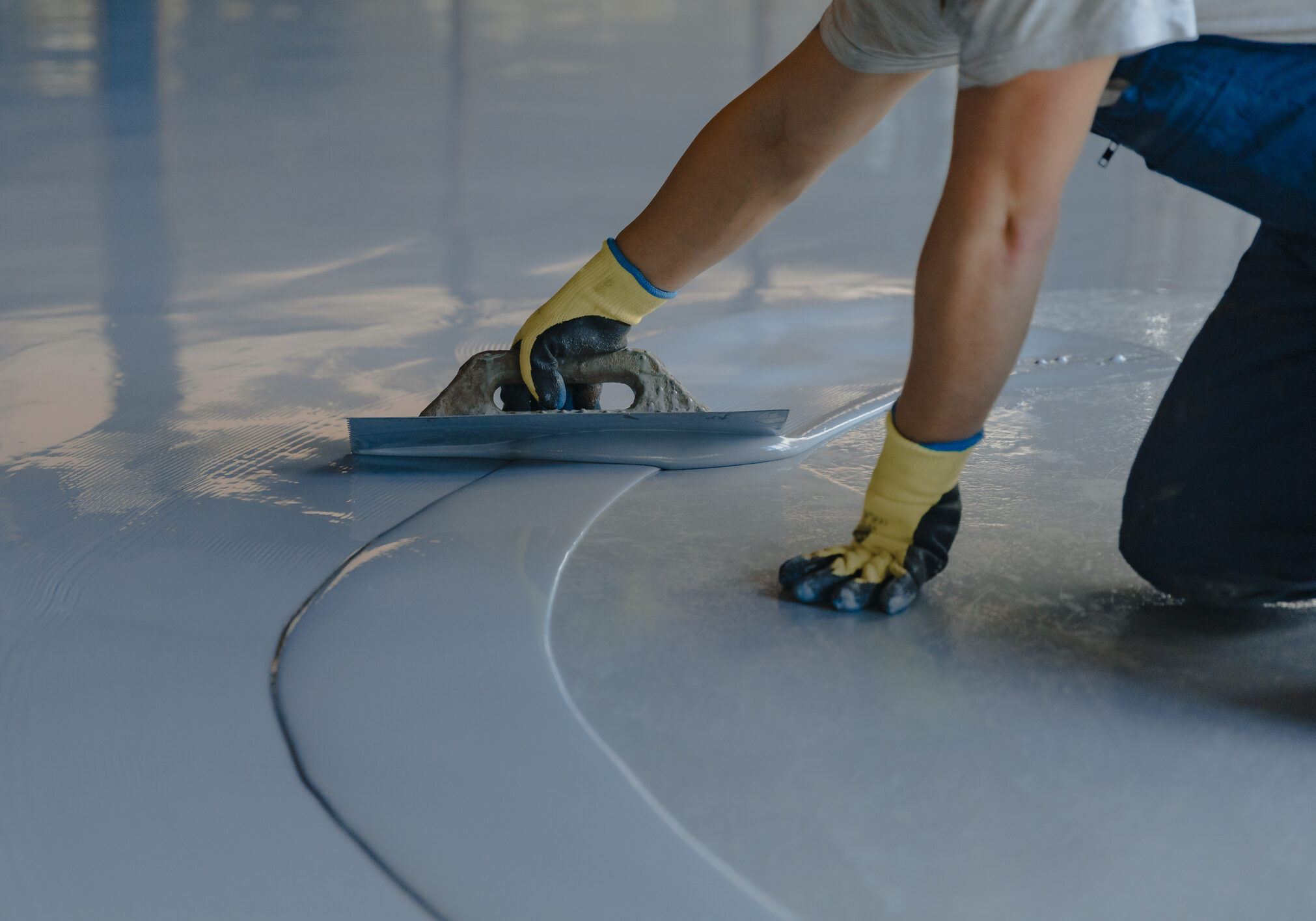 The worker applies gray epoxy resin to the new floor